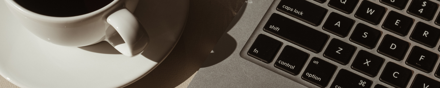 A cup of tea and an open lap-top on a desk