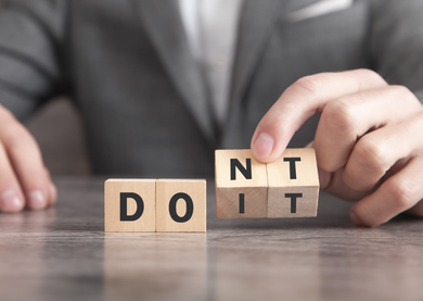 Male in a suit, lifting letter blocks that spell 'do it' and 'don't do it'.