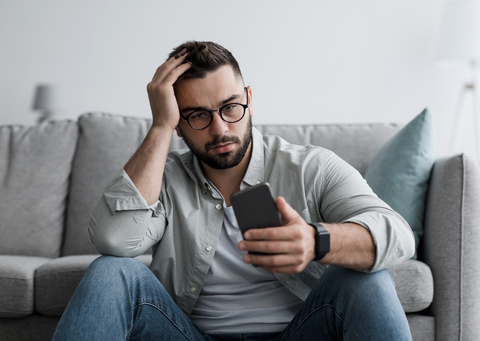 A male looking at his phone anxiously
