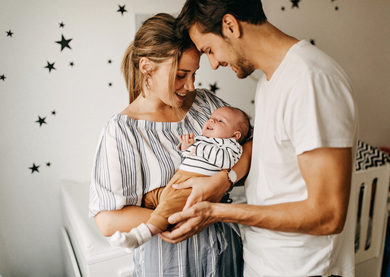 Parents holding their new-born baby at home.