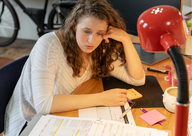 A female employee looking tired and bored at work, surrounded by paperwork.